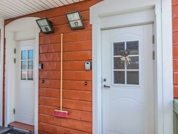 A house with two white doors, each with a number above it, and a broom leaning against the wall.