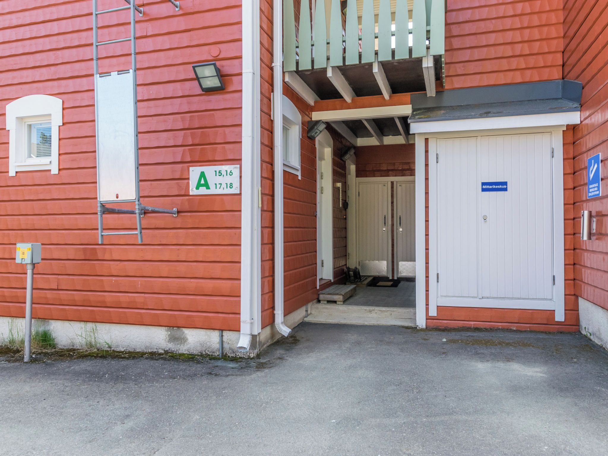 A red building with a white door and a blue sign indicating a medical facility.