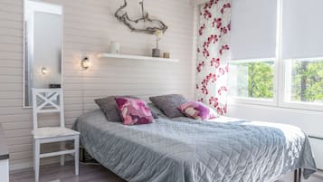 Ein Schlafzimmer mit einem Bett, einem Nachttisch, einem Spiegel, einer Wanduhr, einem dekorativen Gegenstand und einem Fenster mit Vorhängen.