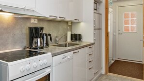 Eine moderne Küche mit weißen Schränken, einem Herd, einer Kaffeemaschine und einer Mikrowelle.
