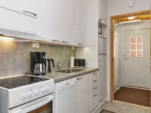 Una cocina moderna con gabinetes blancos, estufa, microondas y cafetera.