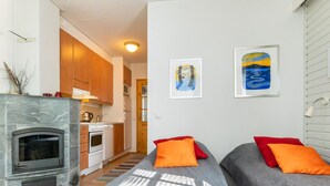 A modern interior with a kitchen, two beds with orange pillows, and artwork on the wall.