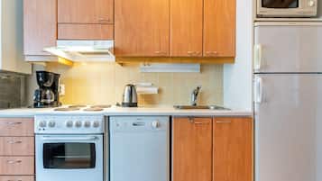 Een keuken met houten kastjes, een fornuis, een vaatwasser, een magnetron en een koffiezetapparaat.