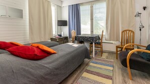 A hotel room with two beds, a table with chairs, a TV, and a window with curtains.