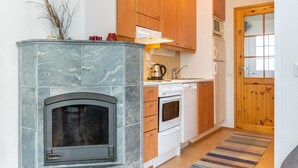 A kitchen with a stone fireplace, wooden cabinets, a microwave, and a stove.