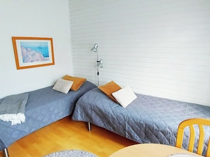 A room with two single beds, a standing lamp, a framed picture on the wall, and a wooden floor. - Rautulampi h22 by Interhome (Inari)