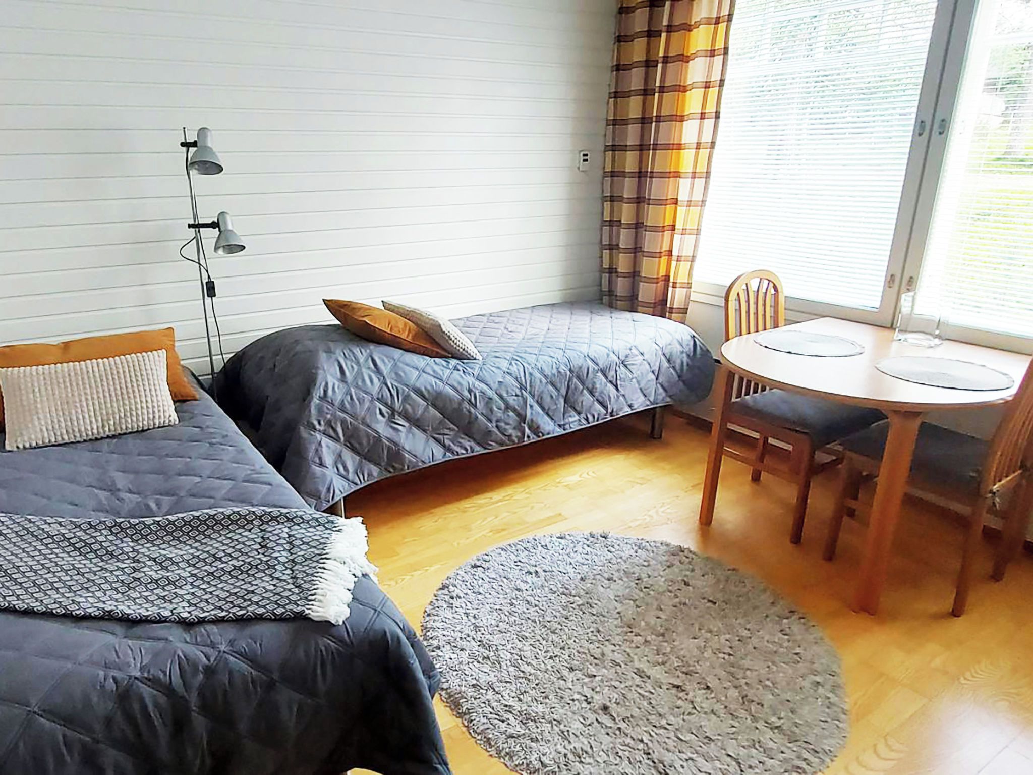 Una habitación pequeña con dos camas, una mesa de comedor y una silla.