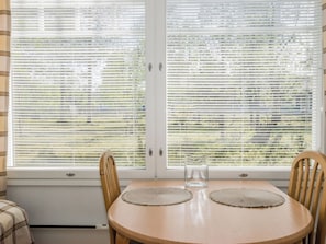 A room with a round wooden table, two chairs, and a window with blinds. - Rautulampi h22 by Interhome (Inari)