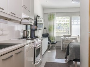 Une cuisine moderne équipée d’une machine à café, d’une bouilloire et d’une cuisinière. Un coin repas avec une table et des chaises est également à disposition.