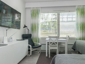 Une chambre d’hôtel équipée d’un bureau, de deux chaises, d’une télévision et d’un lit.