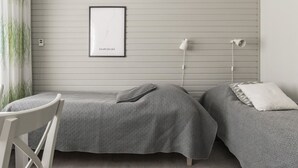 A minimalist bedroom with two beds, a framed map on the wall, and bedside lamps.