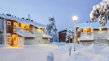 Lumipeitteinen rakennus, jonka ulkoseinät ovat puuta, siinä on parveke ja valaisinpylväs.