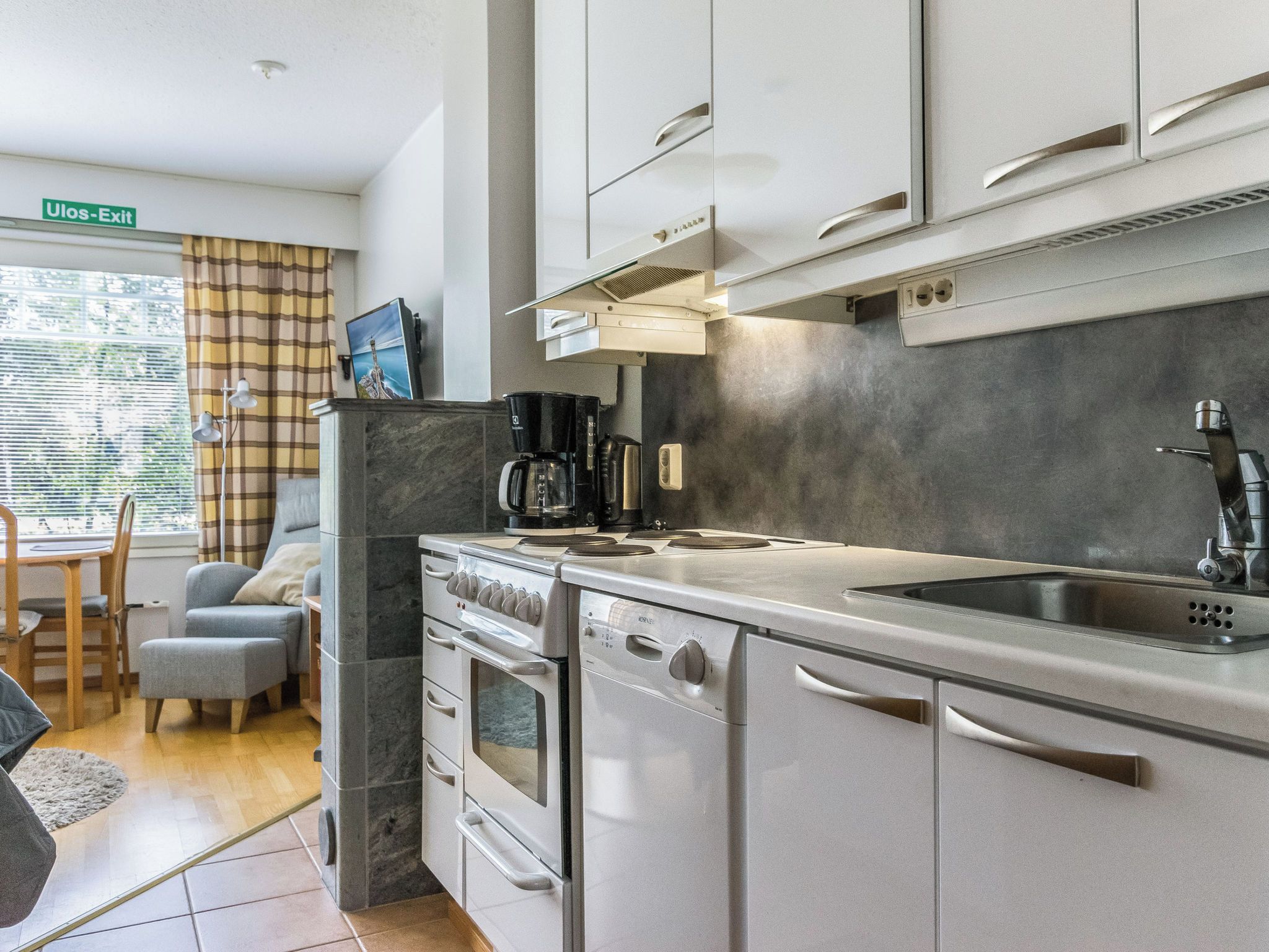 A modern kitchen with a built-in oven, a coffee maker, and a sink.