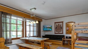 Una habitación acogedora con una mesa de madera, bancos, un sofá y literas.