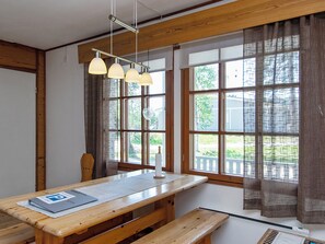 Una habitación con una mesa de madera, bancos y una lámpara colgante.