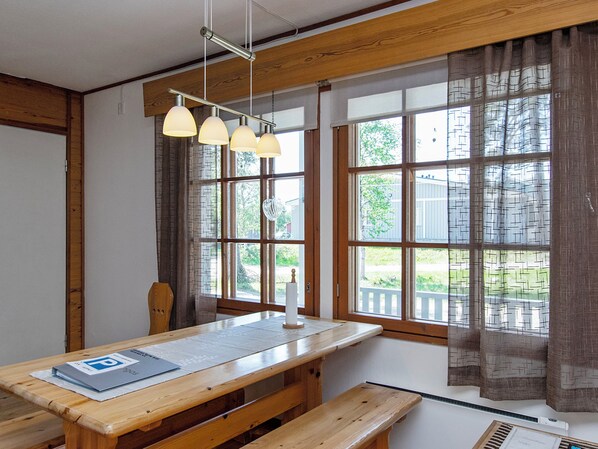 Una habitación con una mesa de madera, bancos y una lámpara colgante.