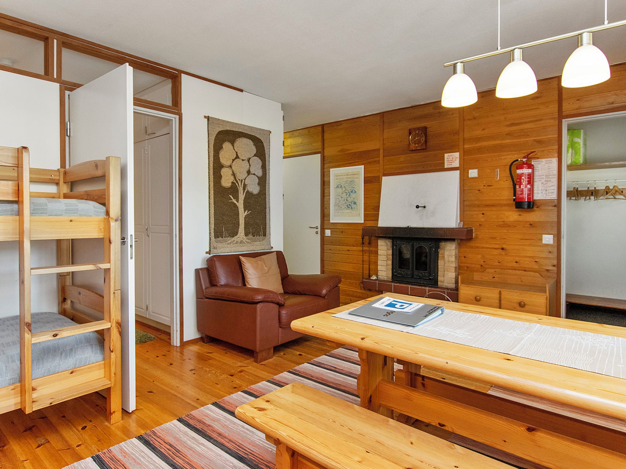 A cozy room with a wooden bunk bed, a brown leather sofa, a wooden dining table, and a fireplace.