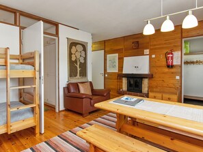 Una habitación acogedora con una cama nido de madera, un sofá de cuero marrón, una mesa de comedor de madera y una chimenea.