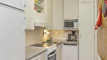 A compact kitchen with white cabinets, a microwave, a coffee maker, and a dishwasher.