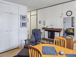 Un espacio habitable compacto con zona de comedor, sofá, chimenea y un reloj en la pared.
