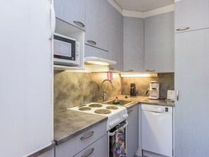 Una kitchenette compacta con microondas, estufa, pileta y lavavajillas Bosch.