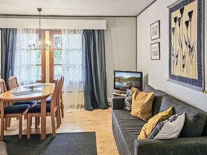 Un salon comprenant une table à manger en bois, des chaises, un canapé, un téléviseur et des œuvres d’art accrochées au mur.