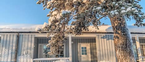 A snow-covered building with a large tree in front.