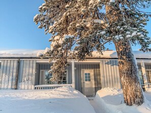 Un edificio cubierto de nieve con un árbol grande en primer plano.