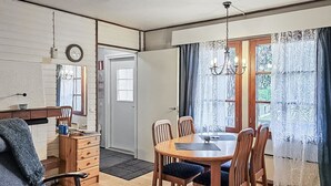 A dining area with a wooden table and chairs, a chandelier, and a view of the outdoors through a window with curtains. - Saariseläntie 8 a 8 by Interhome (Inari)