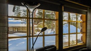 Ett rum med ett stort fönster som ger utsikt över ett snötäckt landskap och en timmerstuga.