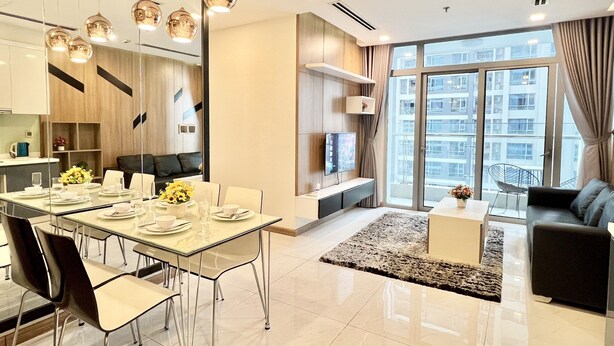 Un salon moderne avec un canapé, un coin repas avec une table dressée pour quatre personnes et une grande fenêtre donnant sur la ville.