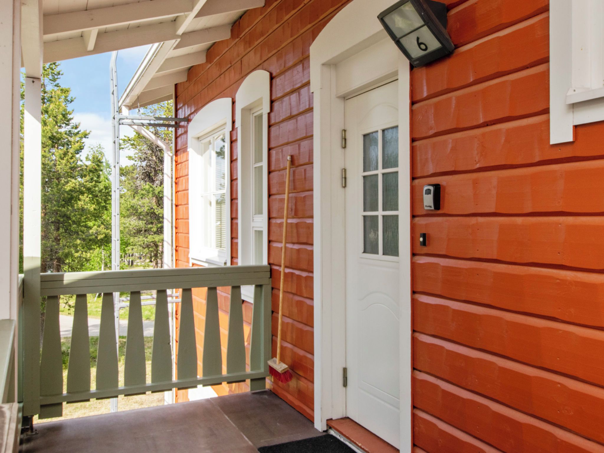 A wooden house with a porch, a white door, and a mailbox.