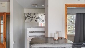 Una habitación con cama, una mesita con velas, un reloj en la pared y una ventana con cortinas.