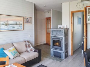 A cozy living room with a fireplace, a sofa with decorative pillows, and a painting on the wall.