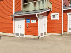 En rød bygning med hvide døre og en balkon. Skilte viser rumnumre og et område for rygning.