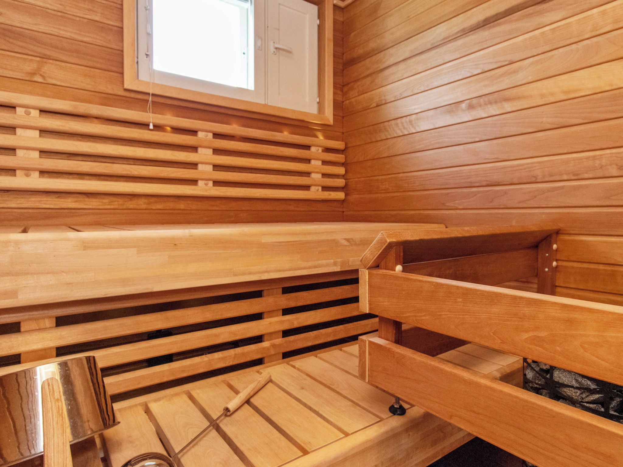 Un sauna avec des bancs en bois, une fenêtre et un plancher en bois.