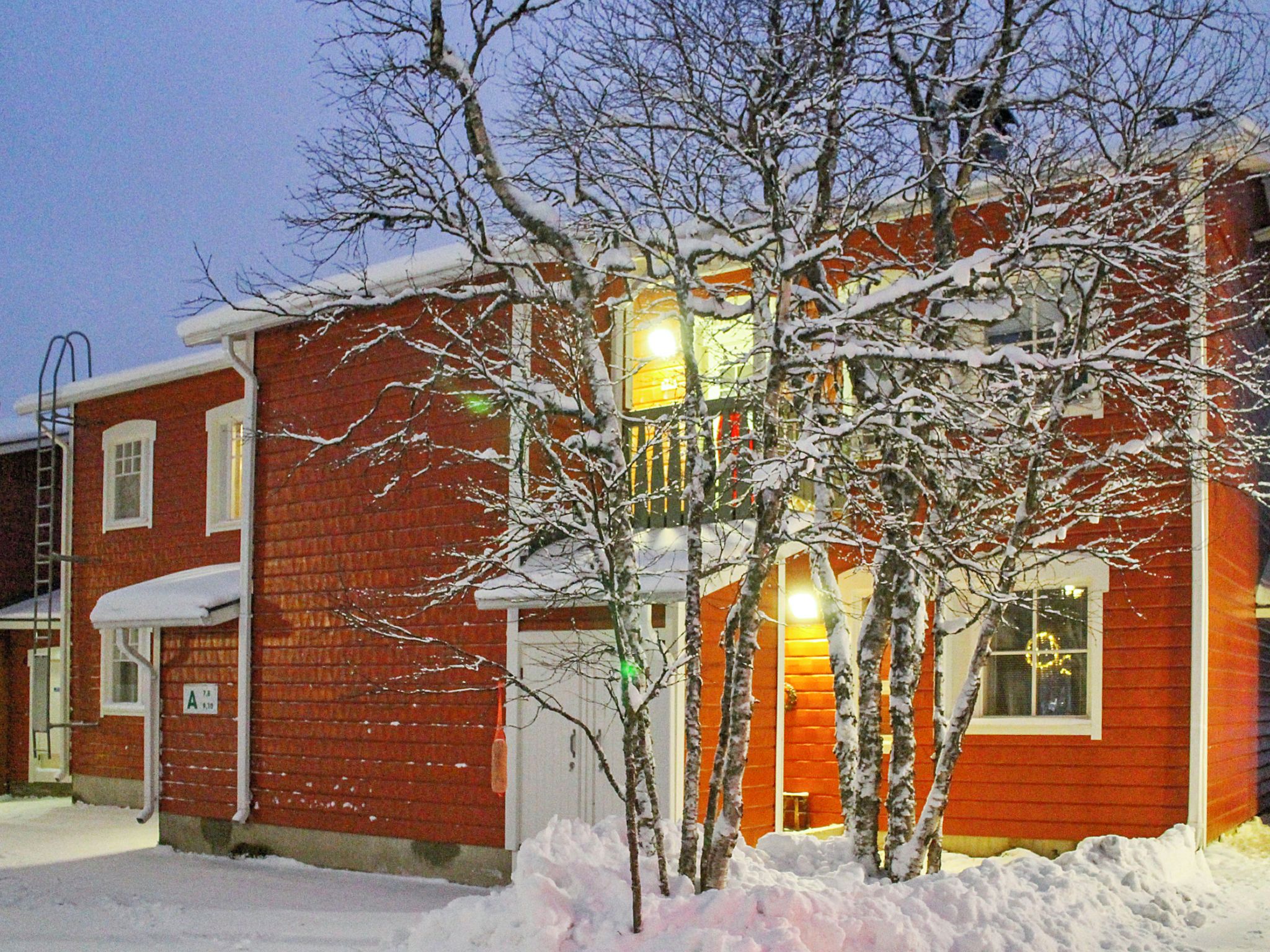 A red brick building with a two-story structure, a visible garage door, and a snow-covered landscape.