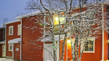 A red brick building with a two-story structure, a visible garage door, and a snow-covered landscape.