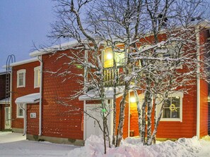 A red brick building with a two-story structure, a visible garage door, and a snow-covered landscape.