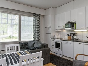 Et kompakt køkken med hvide skabe, en mikrobølgeovn og en komfur.
