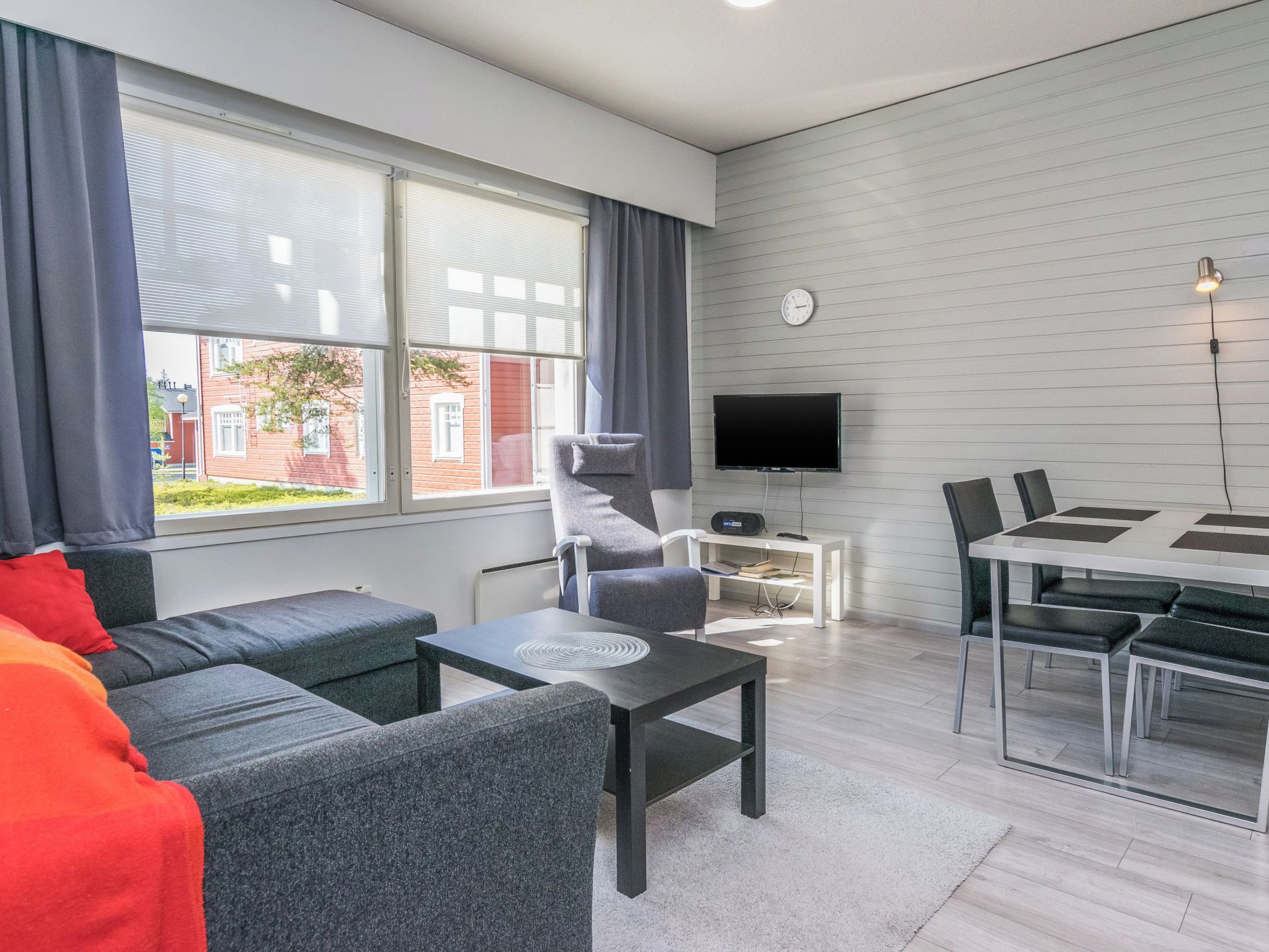 Un salon moderne comprenant un canapé, un fauteuil, une table basse et un coin repas avec des chaises et une table.
