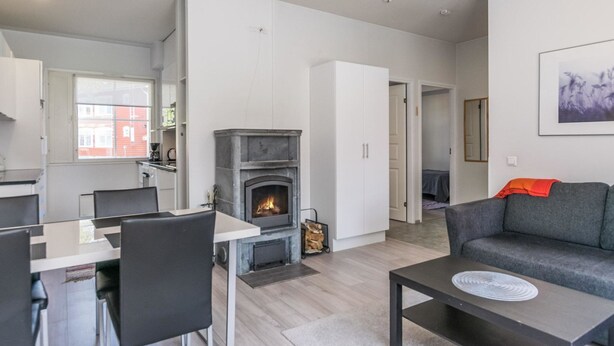 A modern living room with a fireplace, a dining area with chairs, and a sofa with a throw blanket.