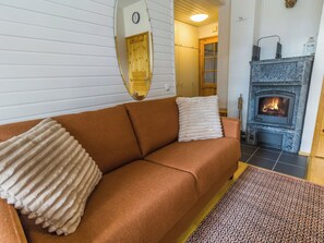 Een gezellige woonkamer met een bruine bank, een open haard en een kamerkleed met een patroon.