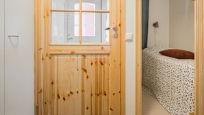 Een houten deur met een raam, die leidt naar een slaapkamer met een bed en een kussen.
