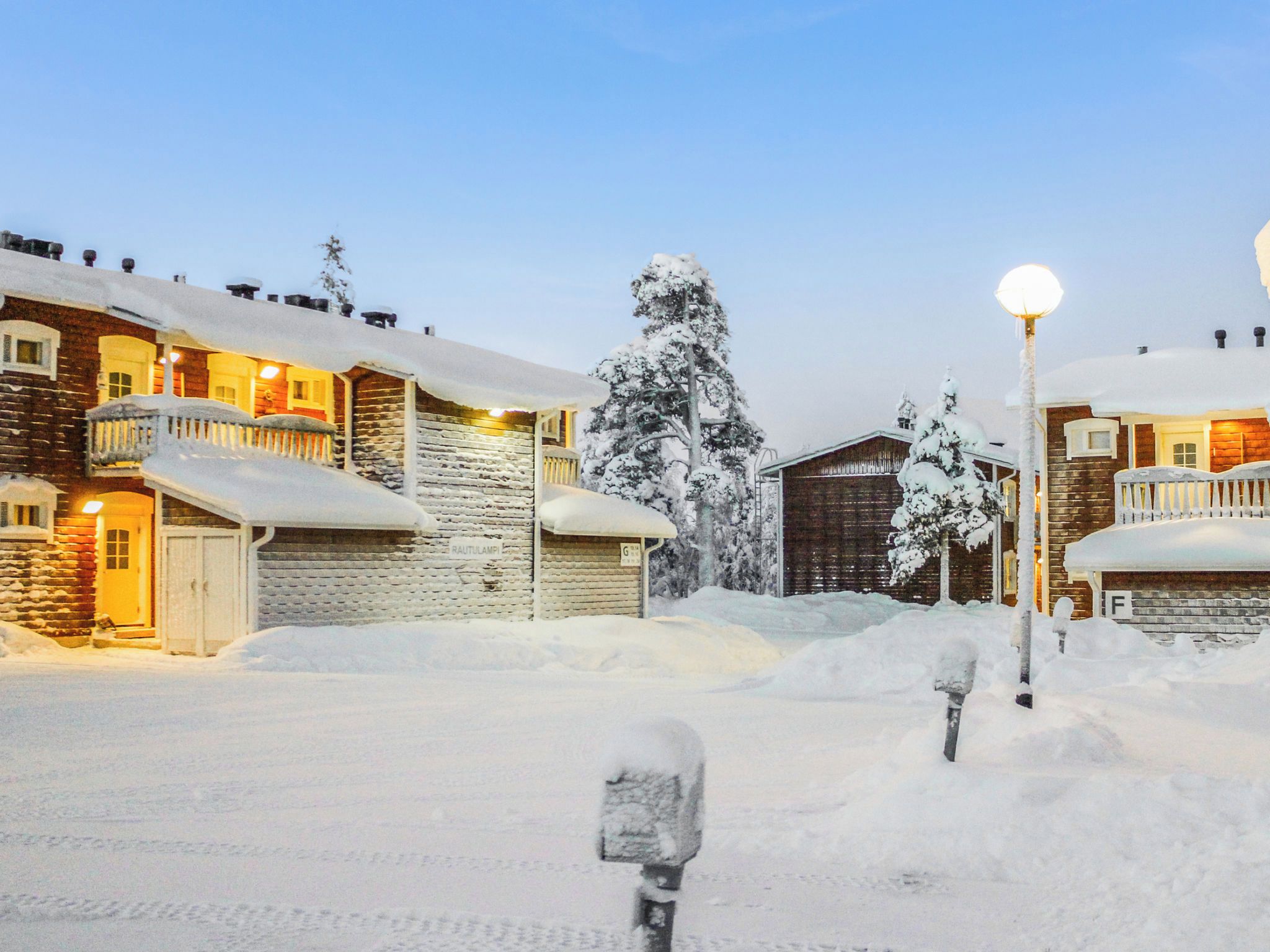 Een besneeuwde woonwijk met huizen, voorzien van balkons en houten gevels.
