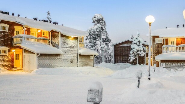 Un quartier résidentiel enneigé, avec des maisons, un garage et un lampadaire.