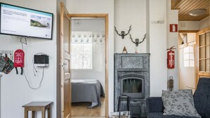 Un salon confortable avec une cheminée, un téléviseur fixé au mur et une petite table.
