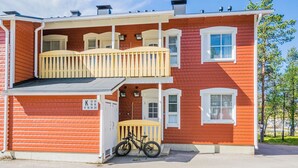 Un immeuble de deux étages doté d’un balcon, de portes numérotées et d’un vélo garé à l’extérieur.