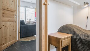 Une pièce comprenant une armoire en bois, une petite table en bois, un lit recouvert d’une courtepointe et une lampe de bureau.