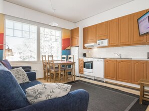 Una cocina moderna con armarios de madera, un comedor con mesa y sillas, y un ventanal que proporciona luz natural.